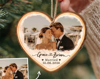 May include: A heart-shaped wooden ornament featuring a printed photograph of a couple in wedding attire. The text "Grace & Brian" is printed below the photo, followed by "Married" and the date "12.06.2026" with small heart icons.