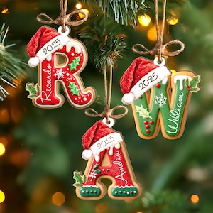 Pu&ograve; includere: Addobbi natalizi a forma di lettere R, W e A, ciascuno con un cappello da Babbo Natale e l'anno 2025. Gli ornamenti sono rossi e verdi con nomi come Ricardo, William e Amelia. Sono appesi con dello spago.