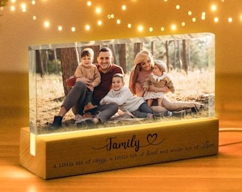 Puede incluir: Un marco de fotos de madera con una luz blanca cálida ilumina una foto familiar de cuatro personas. El marco tiene una cita que dice "Familia, un poco de locura, un poco de ruido y mucho amor."