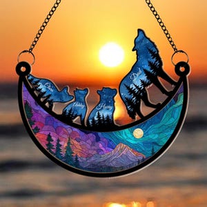 May include: A decorative wall hanging featuring a wolf howling at the moon, with the names "Dad", "Claire", "Ashley", and "Harry" inscribed. The design includes a mountain scene and a starry night sky, with a chain for hanging.