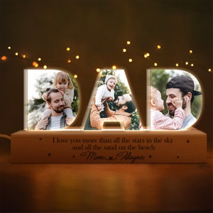 May include: A wooden light-up sign spelling "DAD" with three photos of a father and his children. The sign has a message that reads "I love you more than all the stars in the sky and all the sand on the beach." The message is signed "Mom & Alayna".