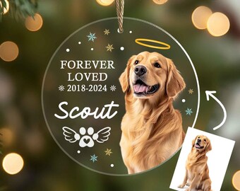 May include: A round, clear acrylic ornament with a white paw print and angel wings. The ornament has the text "Forever Loved *2018-2024* Scout" and a picture of a golden retriever.