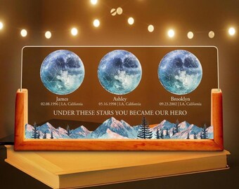 May include: A wooden framed illuminated sign with three moon constellation designs. Each moon has a name and date printed below it. The text "UNDER THESE STARS YOU BECAME OUR HERO" is printed below the moons.