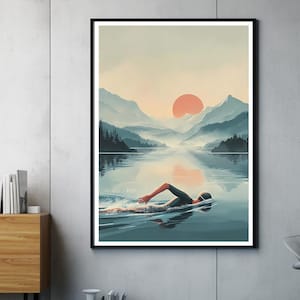 Op de afbeelding: Een ingelijste kunstdruk toont een zwemmer in een meer, met bergen en een zonsondergang op de achtergrond. Het kunstwerk gebruikt koele blauw- en groentinten, met een warme oranje zon.