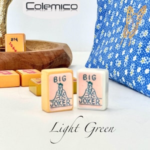 May include: Mahjong tiles with "BIG JOKER" text and a graphic of a figure. The tiles are light orange and white. A blue floral patterned bag is in the background. The word "Colemico" is at the top. The words "Light Green" are at the bottom.