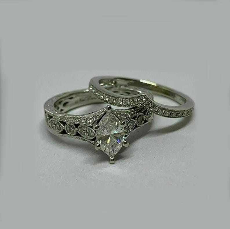 May include: A silver engagement ring set with a large marquise-shaped diamond and smaller diamonds set in a delicate filigree design.