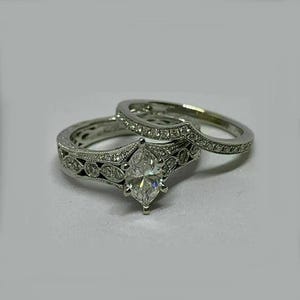 May include: A silver engagement ring set with a large marquise-shaped diamond and smaller diamonds set in a delicate filigree design.