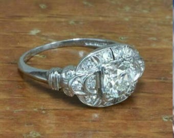 May include: A silver engagement ring with a large, clear, round diamond set in a filigree design. The ring is surrounded by smaller diamonds.