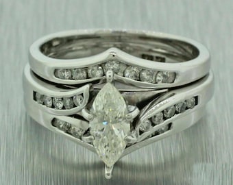 May include: A pear-shaped diamond engagement ring set with a matching wedding band. Both bands are set with small diamonds in a pave setting.