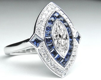 May include: A marquise-cut diamond engagement ring set in platinum with a halo of blue sapphires and smaller diamonds.
