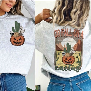 May include: A gray sweatshirt with a graphic of a jack-o'-lantern with a cactus and ghosts on the front and the text "Go Fall on a Cactus" on the back.