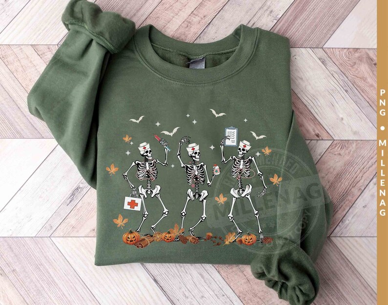May include: Green sweatshirt with a graphic of three skeletons dressed as nurses. The skeletons are holding medical supplies and are surrounded by fall leaves and pumpkins.