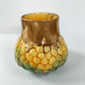 May include: A ceramic vase with a textured, honeycomb-like design in shades of yellow, green, and brown.