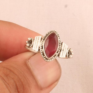May include: A silver ring with a red gemstone set in a detailed silver setting.