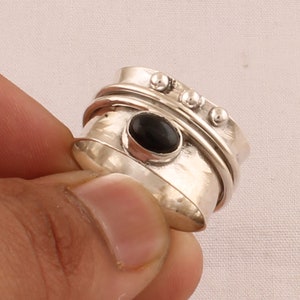 May include: A silver spinning ring with a black oval gemstone and decorative silver beads.