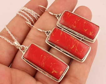 May include: A set of red coral jewelry with silver chain and earrings. The pendant and earrings feature a rectangular red coral stone with a marbled pattern.