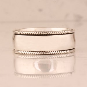 May include: A silver ring with a rope-like design around the edge.