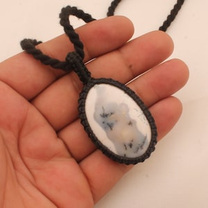 May include: A black cord necklace with an oval-shaped pendant featuring a white and gray agate stone with black dendritic patterns.