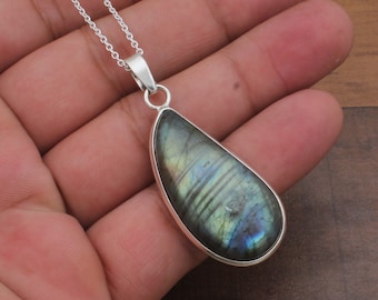 May include: A silver chain necklace with a teardrop-shaped pendant featuring a green and blue labradorite gemstone.