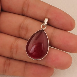 May include: A teardrop-shaped pendant with a deep red gemstone set in sterling silver.