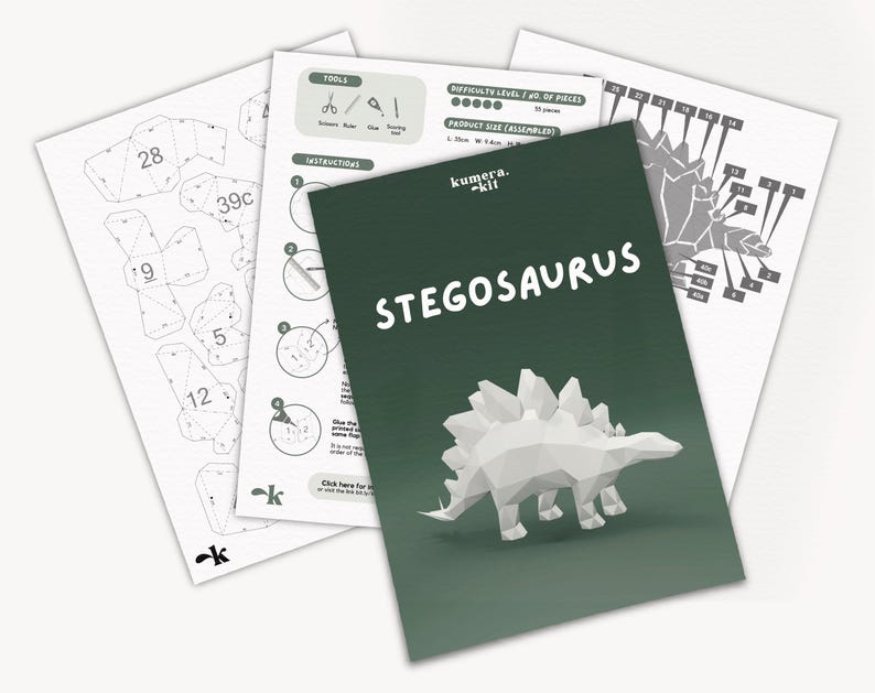 May include: A papercraft kit for building a Stegosaurus dinosaur. The kit includes instructions, a diagram, and a green background with the title "kumera. kit STEGOSAURUS".
