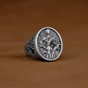 May include: A silver ring featuring an intricate design of a woman standing in a forest with a full moon in the background.