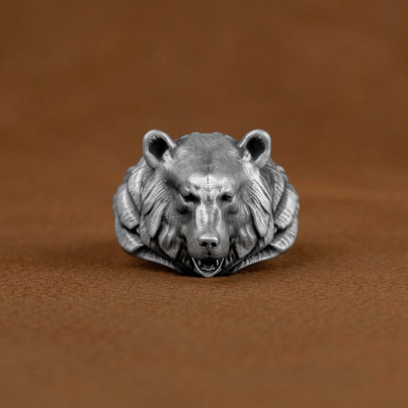 May include: A silver bear head ring with detailed fur and a snarling expression.