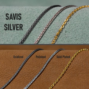 May include: Three silver chains, one oxidised, one polished, and one gold plated. The chains are laid out on a brown surface. The text "SAVIS SILVER" is visible in the top left corner of the image.