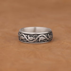Puede incluir: Un anillo de plata con un dise&ntilde;o intrincado de enredaderas y hojas entrelazadas.