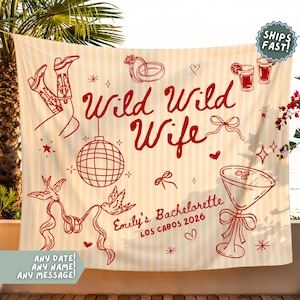 May include: A cream-colored banner with red illustrations and text. The banner reads "Wild Wild Wife" and "Emily's Bachelorette Los Cabos 2026." The design includes cowboy boots, a disco ball, and cocktail glasses. The banner is hanging outdoors.