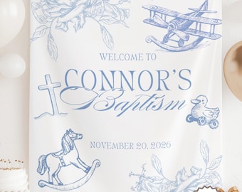 May include: A white banner with blue illustrations and text that reads "Welcome to Connor's Baptism November 20, 2020." The banner features drawings of a cross, flowers, a rocking horse, a duck on wheels, and a biplane.