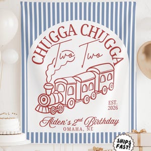 May include: A white and blue striped backdrop with a red train illustration and text that reads "Chugga Chugga Two Two" and "Aiden's 2nd Birthday, Omaha, NE". Balloons and gifts are in the foreground.
