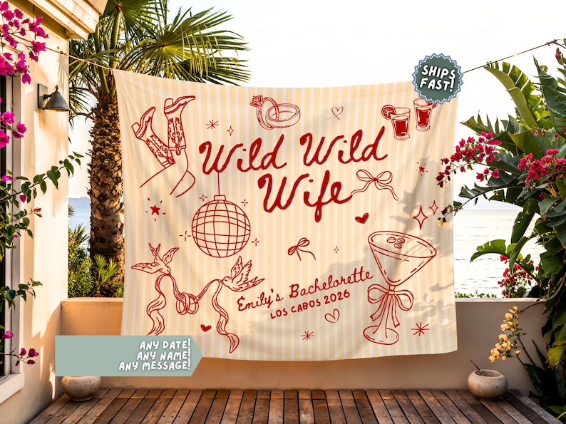May include: A cream-colored banner with red illustrations and text. The banner reads "Wild Wild Wife" and "Emily's Bachelorette Los Cabos 2026." The design includes cowboy boots, a disco ball, and cocktail glasses. The banner is hanging outdoors.