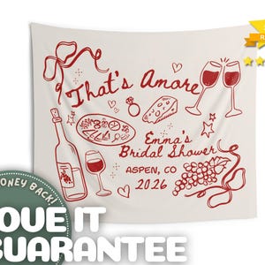 May include: A cream-colored tapestry with red illustrations and text. The design includes wine glasses, a bottle of wine, pizza, cheese, and grapes. Text reads "That's Amore" and "Emma's Bridal Shower, Aspen, CO 2026".