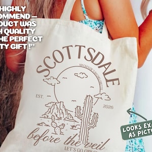 May include: Cream-colored tote bag with a desert-themed design in brown. The design includes the word "Scottsdale", a mountain range, a cactus, and the text "before the veil". The bag also has the text "Looks exactly as pictured".