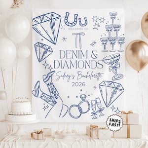 May include: A white backdrop with blue line art for a bachelorette party. The design includes diamonds, cowboy boots, champagne glasses, and the text "Denim & Diamonds Sidney's Bachelorette 2026". White and gold balloons and gifts are in the background.