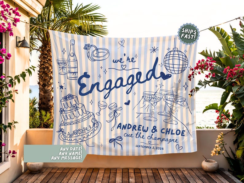 May include: A light blue and white striped fabric banner featuring dark blue line art illustrations of a champagne bottle, wedding rings, a tiered cake, and a disco ball. The text reads "we're Engaged", "ANDREW & CHLOE", "cue the champagne", and "SEPTEMBER 2, 2026".