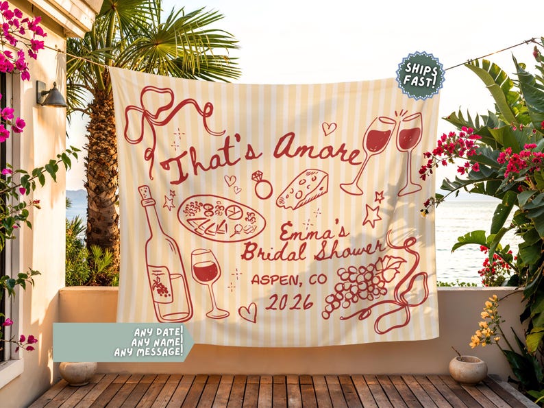 May include: Cream-colored banner with red illustrations and text for a bridal shower. The design includes wine glasses, a bottle, cheese, and the words "That's Amore" and "Emma's Bridal Shower, Aspen, CO 2026".