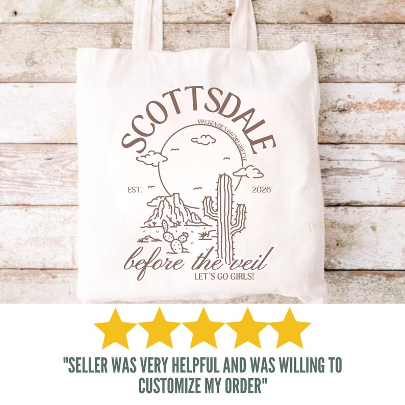 May include: Off-white tote bag with a brown graphic design featuring the word "Scottsdale" in a circular design, a cactus, and the text "before the veil". The bag has two handles and is made of a canvas-like material.