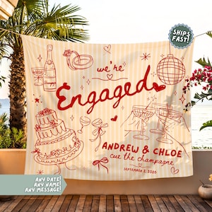 May include: A cream and white striped fabric backdrop featuring red line art illustrations of a champagne bottle, wedding rings, a disco ball, a tiered cake, and cocktail glasses with the text "we're Engaged", "ANDREW & CHLOE", "cue the champagne", and "SEPTEMBER 2, 2026".
