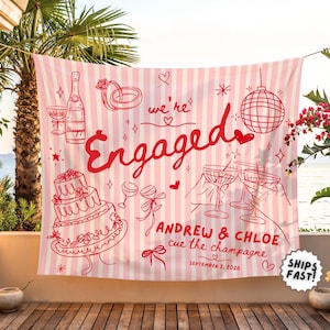 May include: A rectangular fabric banner with vertical light pink and white stripes featuring red line art illustrations of a champagne bottle, wedding rings, a disco ball, a tiered cake, and cocktail glasses with the text "we're Engaged", "ANDREW & CHLOE", "cue the champagne", and "SEPTEMBER 2, 2026".