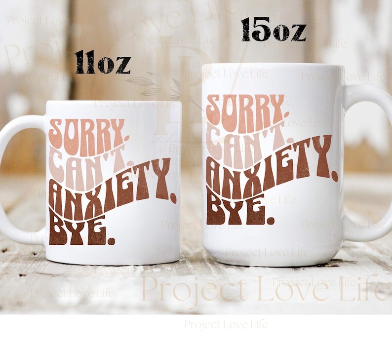 K&ouml;nnte beinhalten: Zwei wei&szlig;e Keramikbecher mit einem braunen, rosa und pfirsichfarbenen Design. Die Becher haben den Text "Sorry Can't Anxiety Bye." Der kleinere Becher ist 11 oz und der gr&ouml;&szlig;ere Becher ist 15 oz.