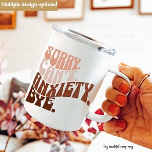 K&ouml;nnte beinhalten: Wei&szlig;e 10oz isolierte Campingtasse mit einem rosa, braunen und wei&szlig;en Design, auf dem "Sorry Can't Anxiety Bye" steht.