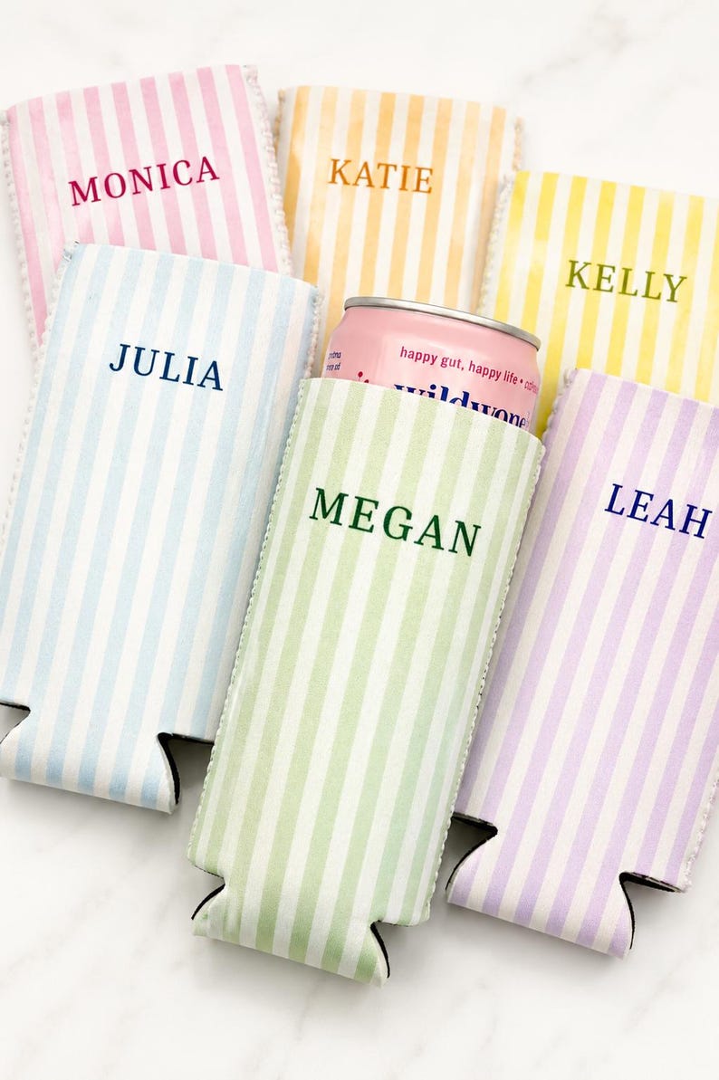 May include: A collection of striped drink koozies in pastel colors, each personalized with a name in a coordinating font. One koozie holds a pink can with the text "happy gut, happy life". The koozies are designed to keep beverages cold.