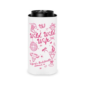 May include: White can cooler with a black top, featuring pink text and illustrations. The text reads "Wild Wild Wife" with "EST. 2026" below. Illustrations include a cowboy boot, disco ball, and martini glass. "Tiffany's Bachelorette, Nashville, TN" is also printed.