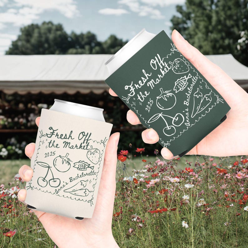 May include: Two beverage can coolers, one cream and one dark green, each with the text "Fresh Off the Market 2025" and a hand-drawn illustration of fruits and vegetables. The text "Anna's Bachelorette" is also included.