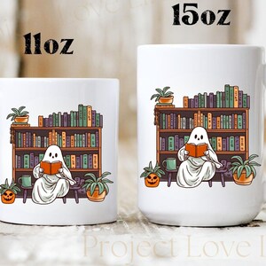 May include: White ceramic mug with a ghost reading a book in front of a bookshelf. The ghost is sitting on a stool with a pumpkin and a plant beside it. The mug has the text "11oz" on the left side and "15oz" on the right side.