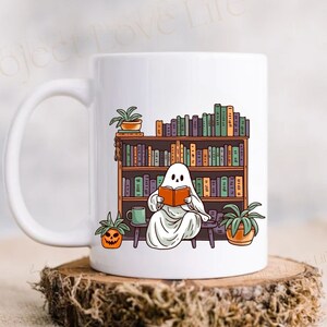 white 15 oz ceramic mug with ghost reading a book with bookshelf and coffee mug, perfect gift for book lovers and a great ghost mug for a gothic friend.