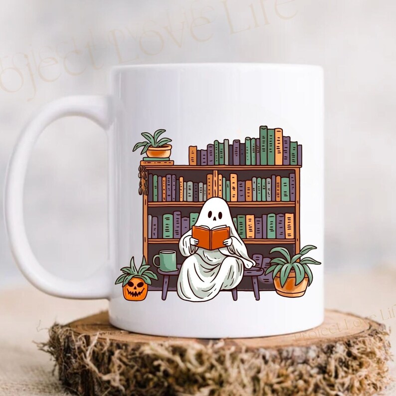 white 15 oz ceramic mug with ghost reading a book with bookshelf and coffee mug, perfect gift for book lovers and a great ghost mug for a gothic friend.
