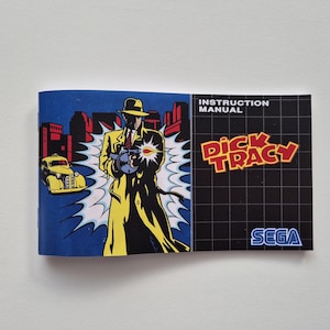 Puede incluir: Un manual de instrucciones de juego Sega Genesis azul y negro para Dick Tracy. La portada presenta una ilustración de dibujos animados de Dick Tracy con un abrigo amarillo sosteniendo un arma, con un coche amarillo en el fondo.